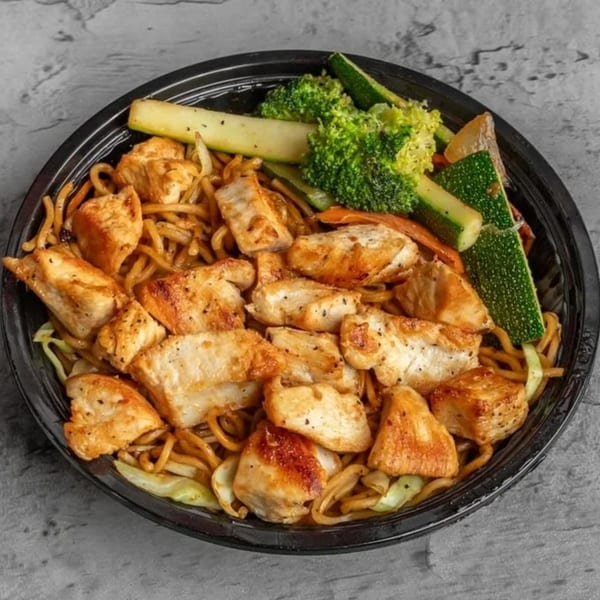 Chicken teriyaki with noodles, zucchini, broccoli, and carrots in a black bowl.